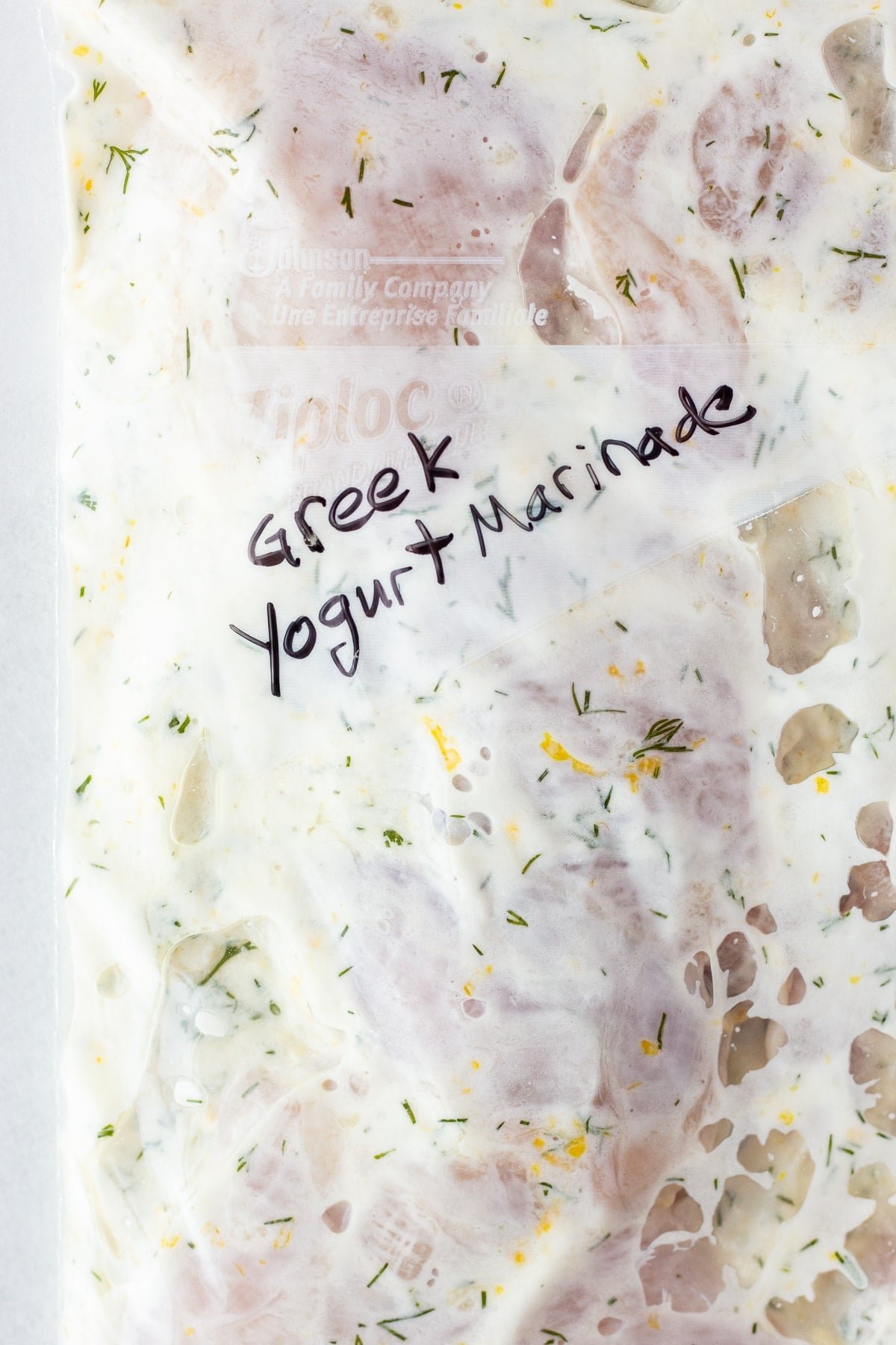 Why is yogurt used in many Greek marinades and dips?